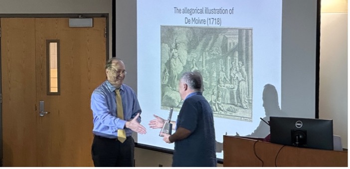 Dr. Rick Travis, Dean of the College of Arts and Sciences at Mississippi State University, presents an MSU cowbell as a gift to Dr. Christian Genest following his lecture on 'The Birth of the Probability Calculus' during the 2024 Murray/Ollivier Address.